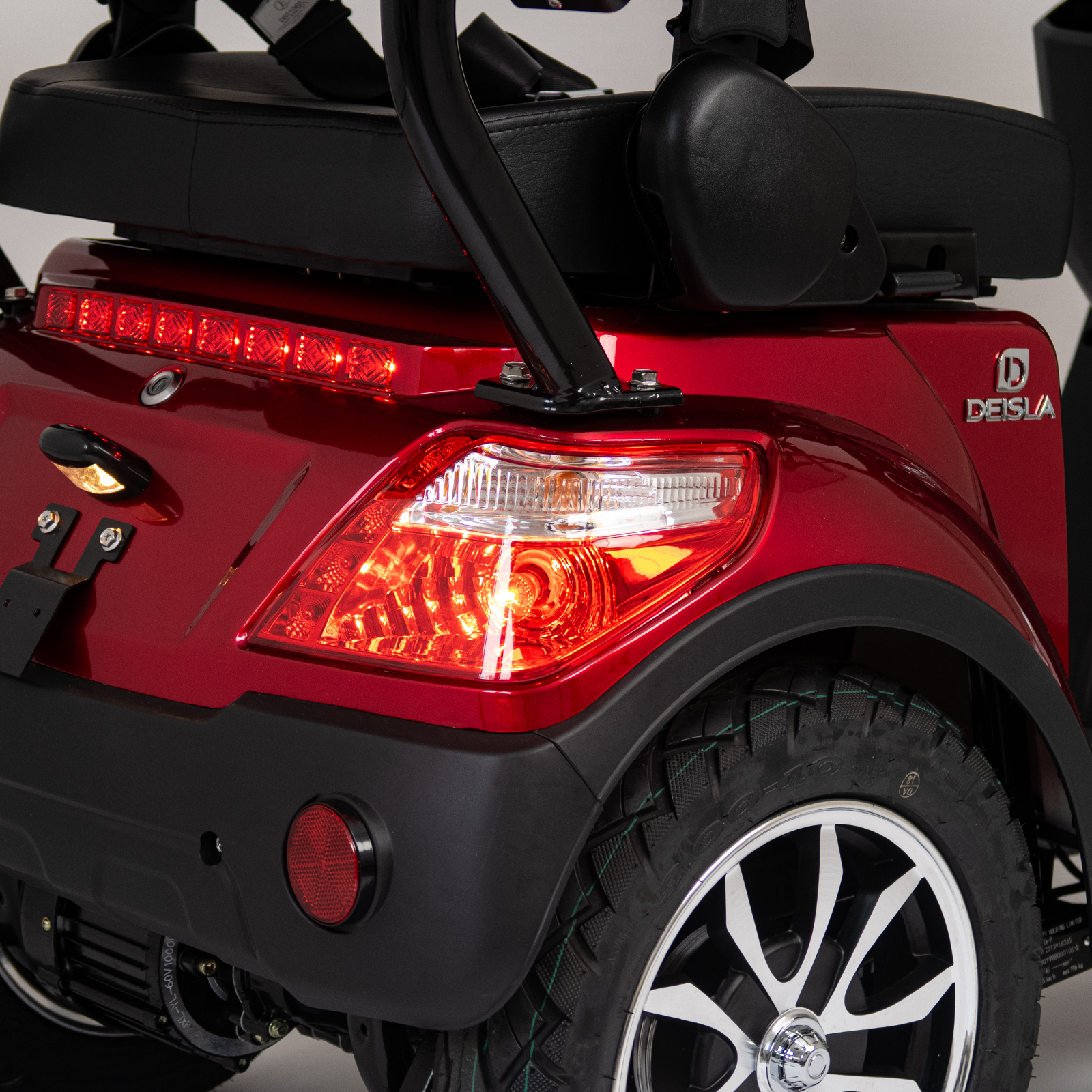 Rückansicht eines roten Mobilitätsrollers. Rücklichter und ein Rad sind sichtbar. Ein schwarzer Sitz ist ebenfalls zu sehen.