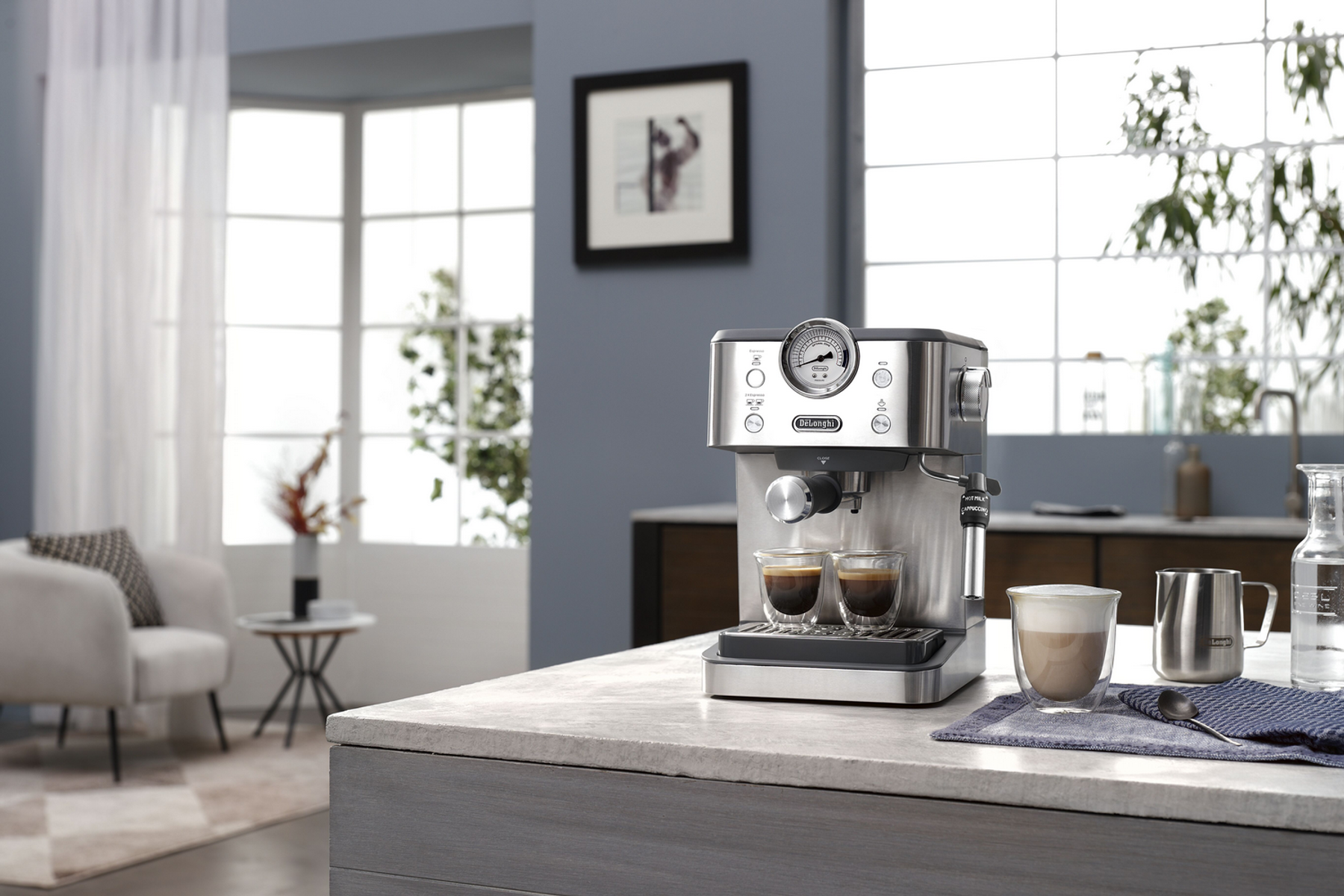 Eine Delonghi Espressomaschine auf einer Theke, mit zwei Kaffeegläsern, in einer Küche.