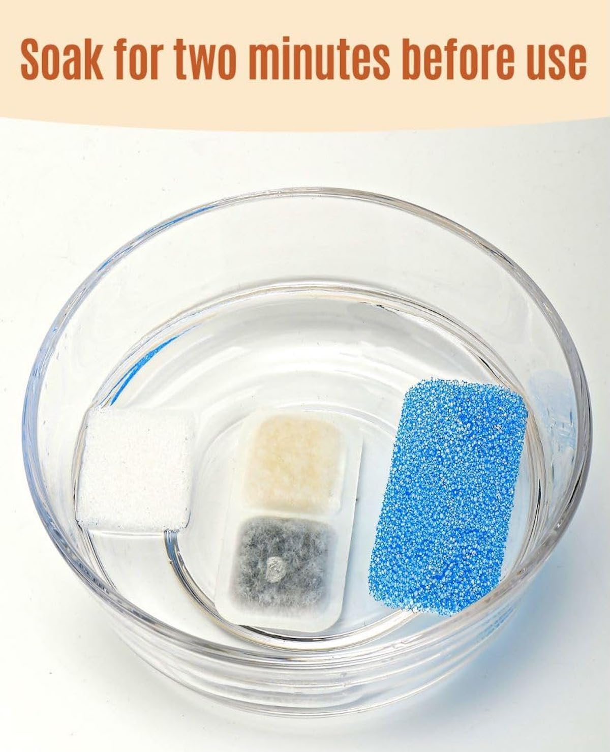 Drei Filterpads in einer durchsichtigen Glasschale mit Wasser. Text sagt 'Zwei Minuten einweichen'.