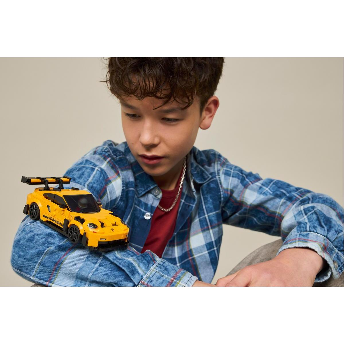 Chłopiec patrzy na żółty samochodzik z czarnym spoilerem.
