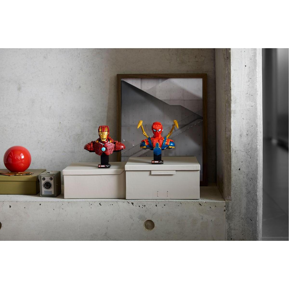 Dwa popiersia LEGO Iron Spider-Man na wystawie. Widoczne jest również popiersie Iron Mana. Znajdują się na szarej powierzchni.