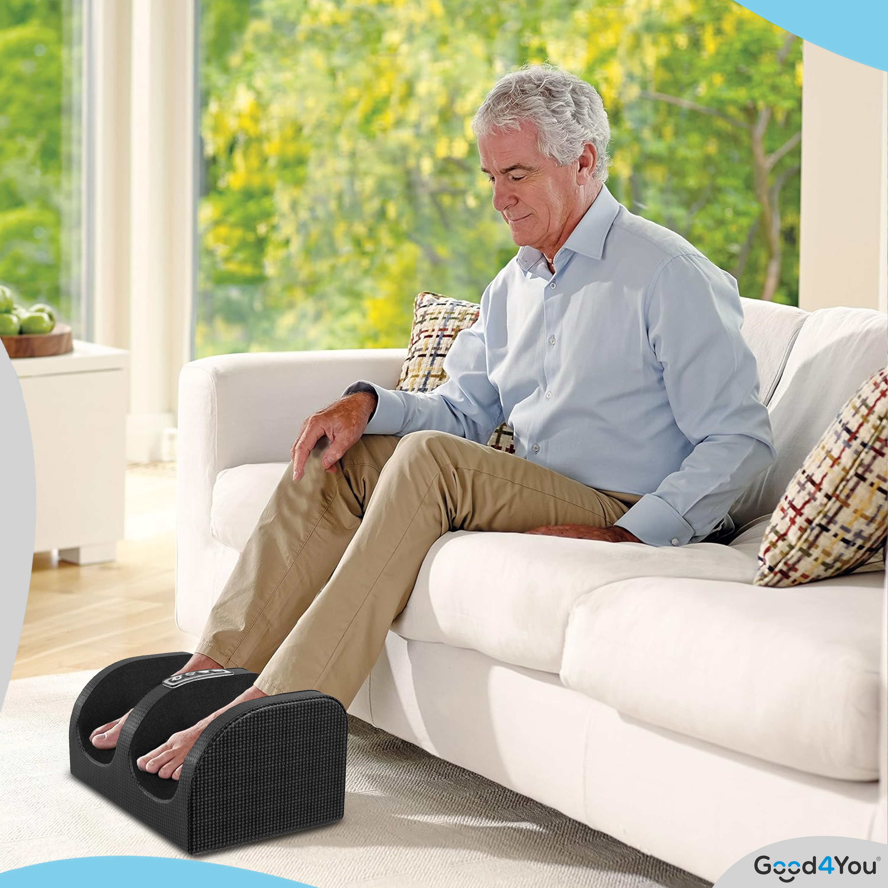 Ein älterer Mann sitzt auf einem Sofa und benutzt ein Fußmassagegerät. Er trägt Freizeitkleidung.
