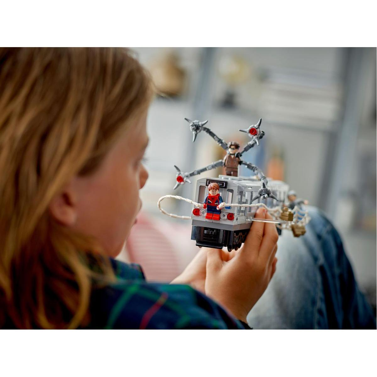 Dziecko trzyma scenę z metra Lego Spider-Man, skupiony wyraz twarzy.