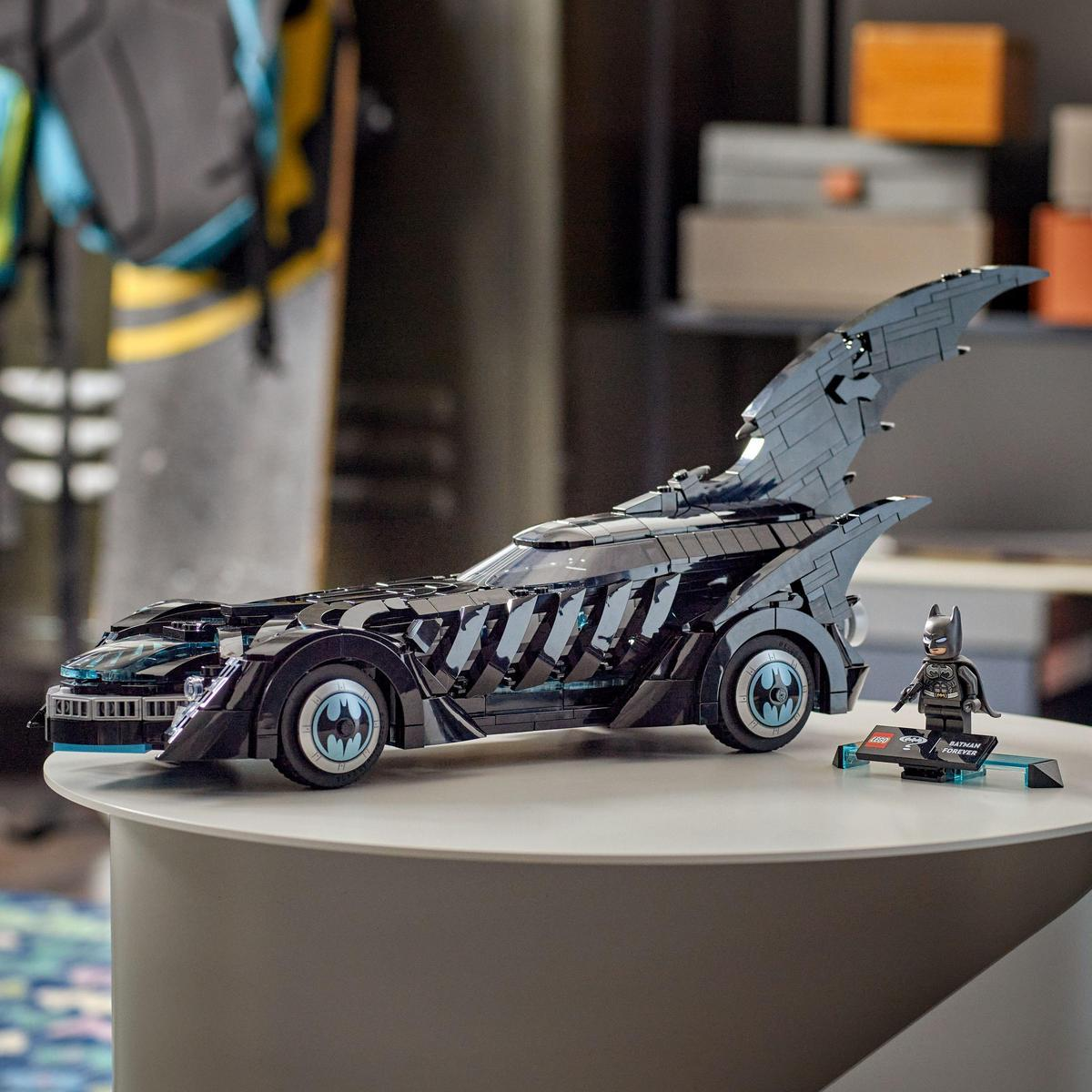 Un Batmobile Lego su un tavolo bianco con una figura di Batman accanto.