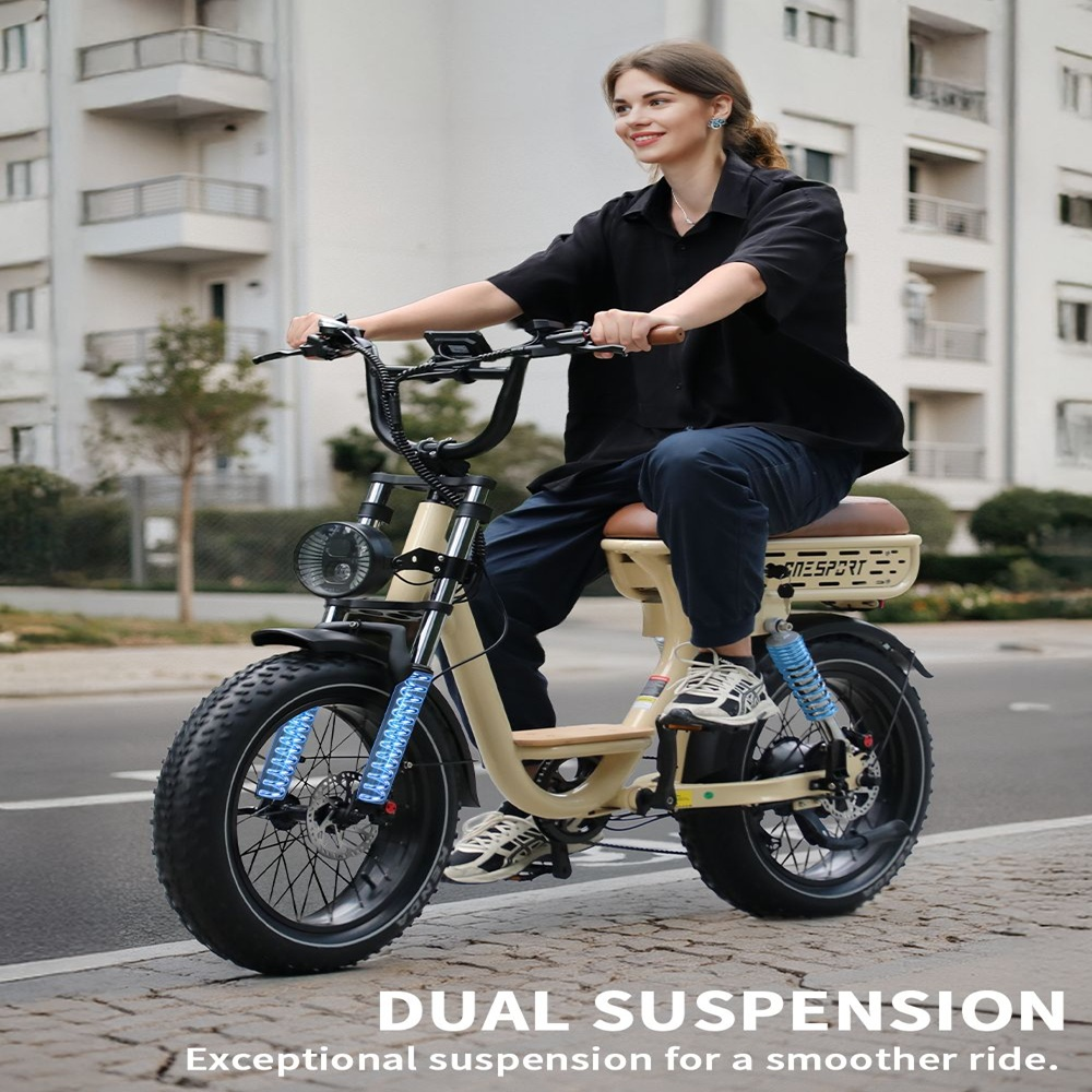 Mujer montando e-bike crema en carretera, doble suspensión, asiento marrón, neumáticos negros.