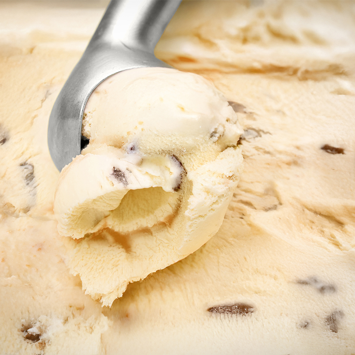 Uno scoop scava nel gelato alla noce pecan al burro; il gelato è marrone chiaro con pezzi di noce pecan marrone scuro.