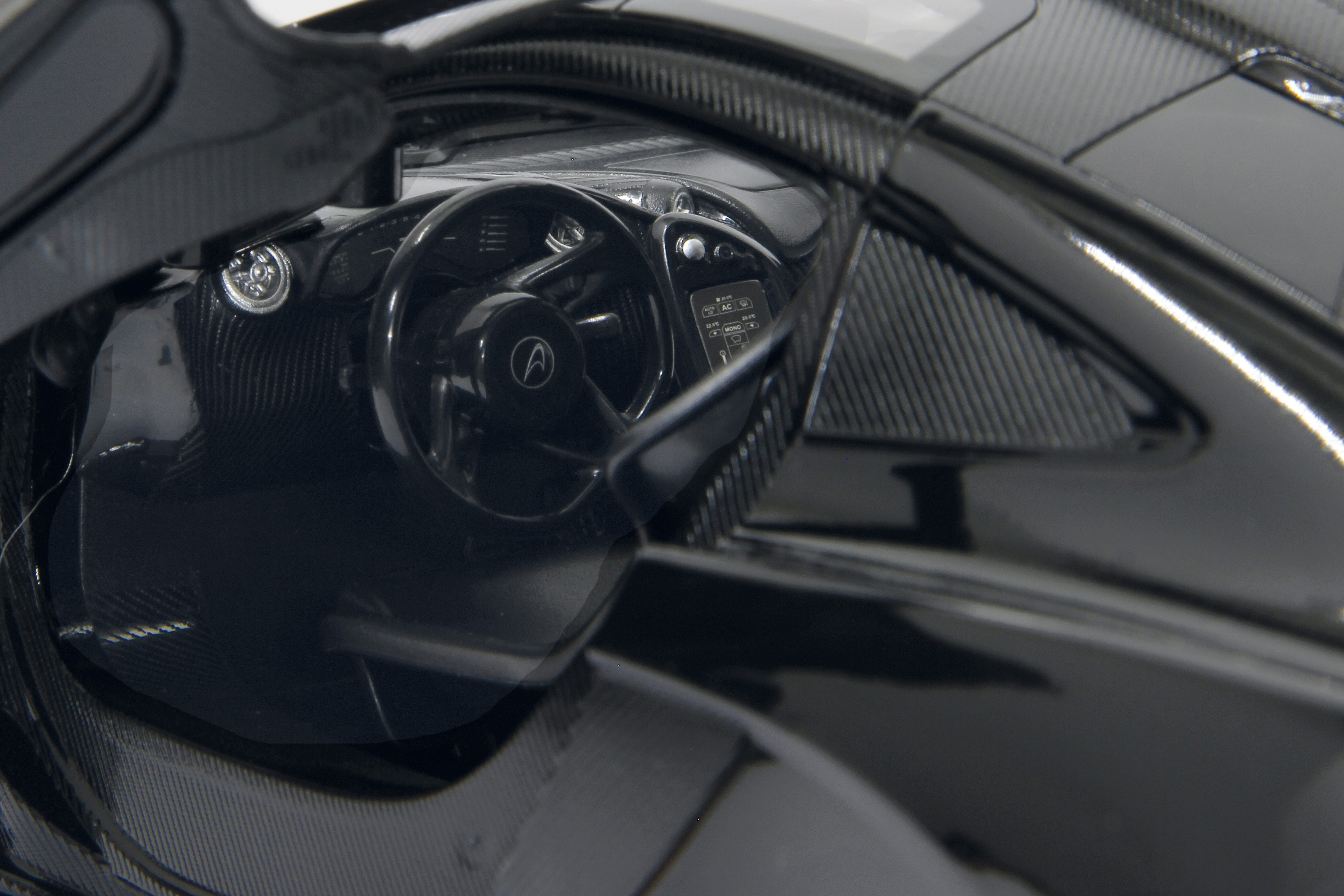 Nahaufnahme des Innenraums eines schwarzen McLaren P1, der das Lenkrad zeigt.