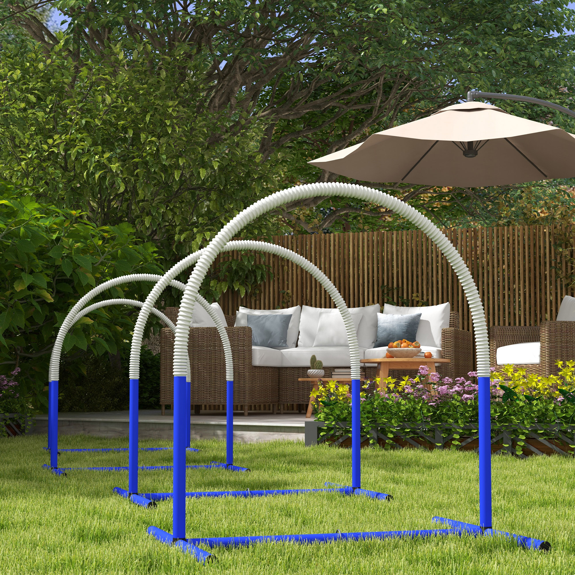Tres aros de agilidad azules con tuberías flexibles blancas sobre hierba verde en un jardín.