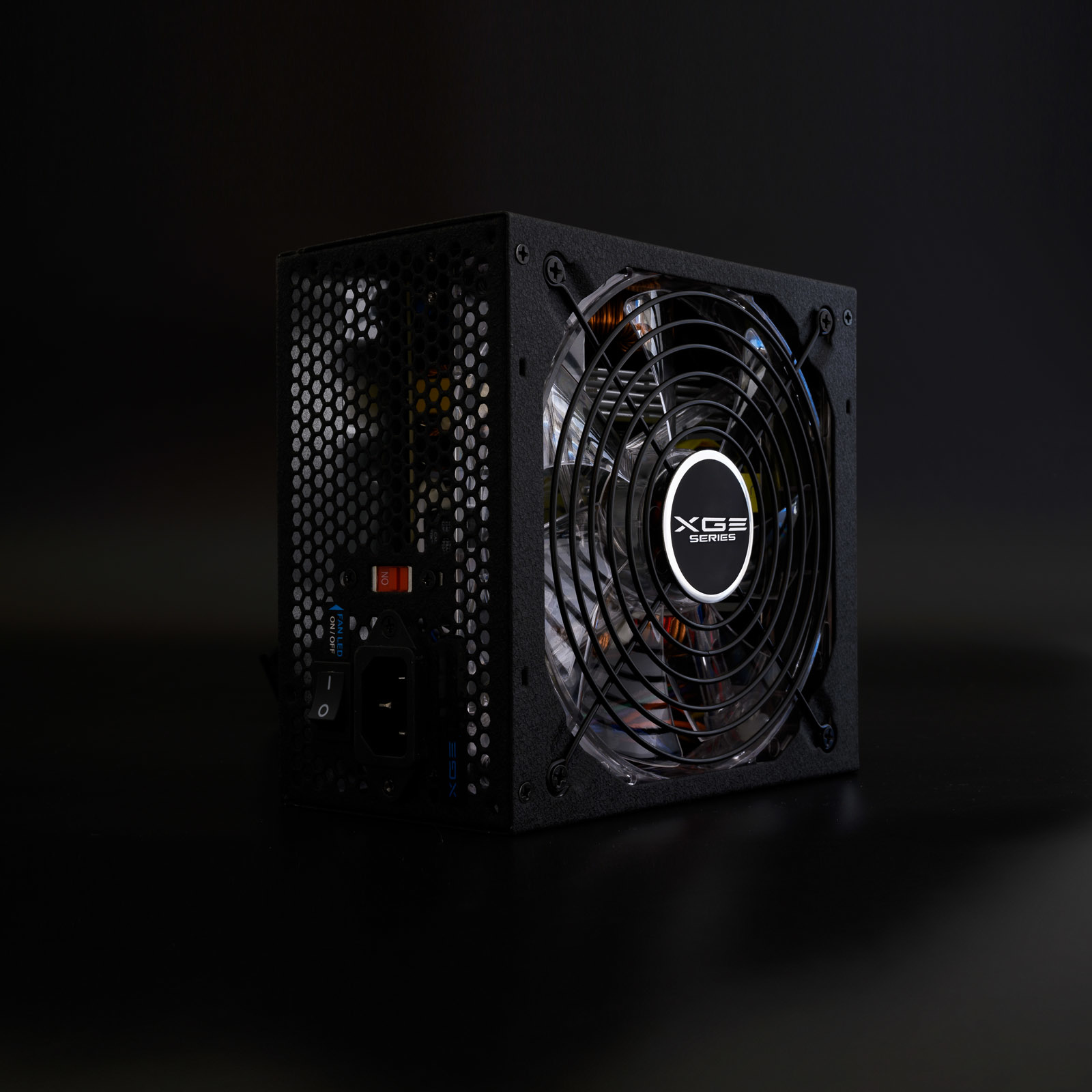 Een zwarte voedingseenheid met een ventilator en XG Series-logo op een donker oppervlak, van opzij bekeken.