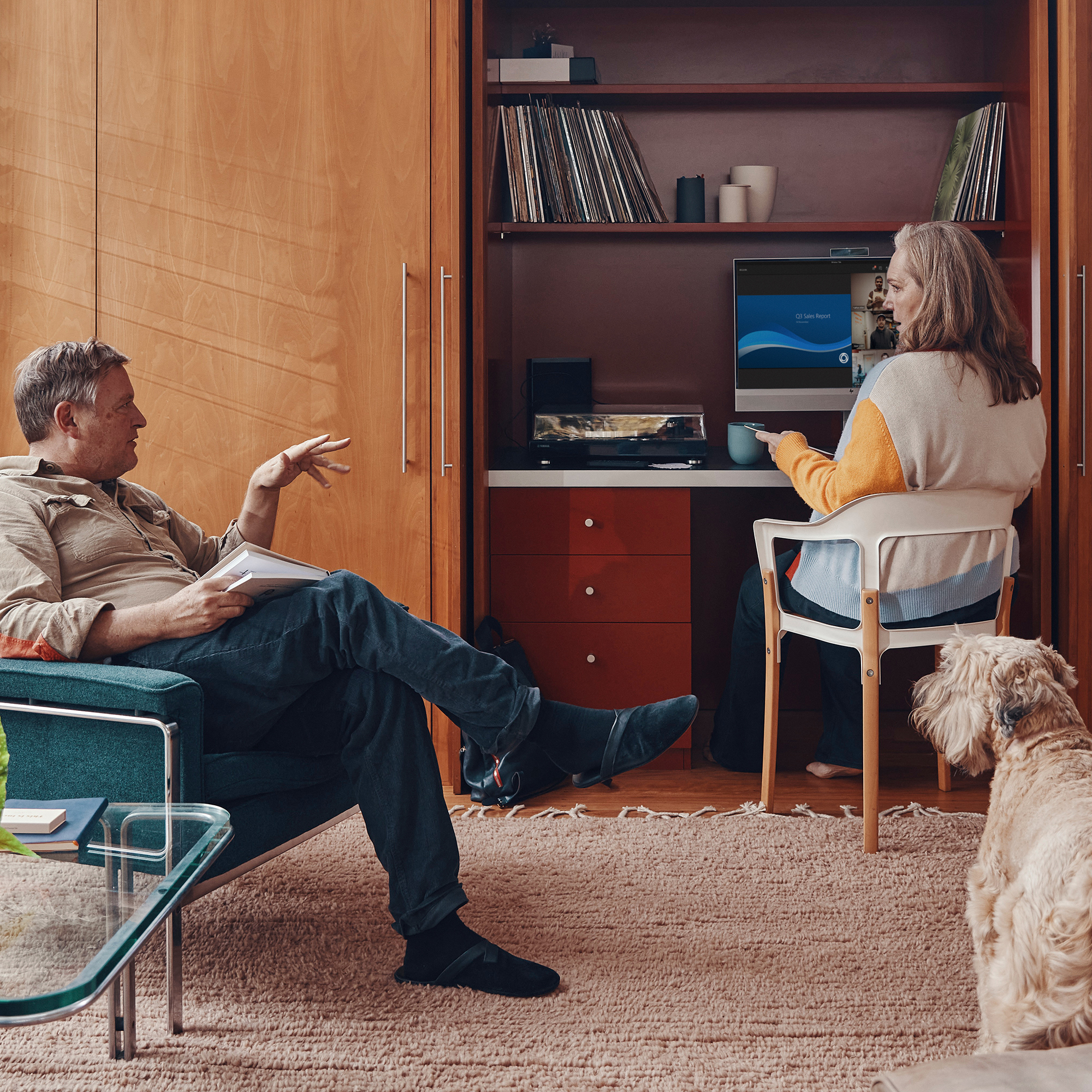 Mężczyzna i kobieta są w pokoju, z psem na pierwszym planie i komputerem na biurku w tle.