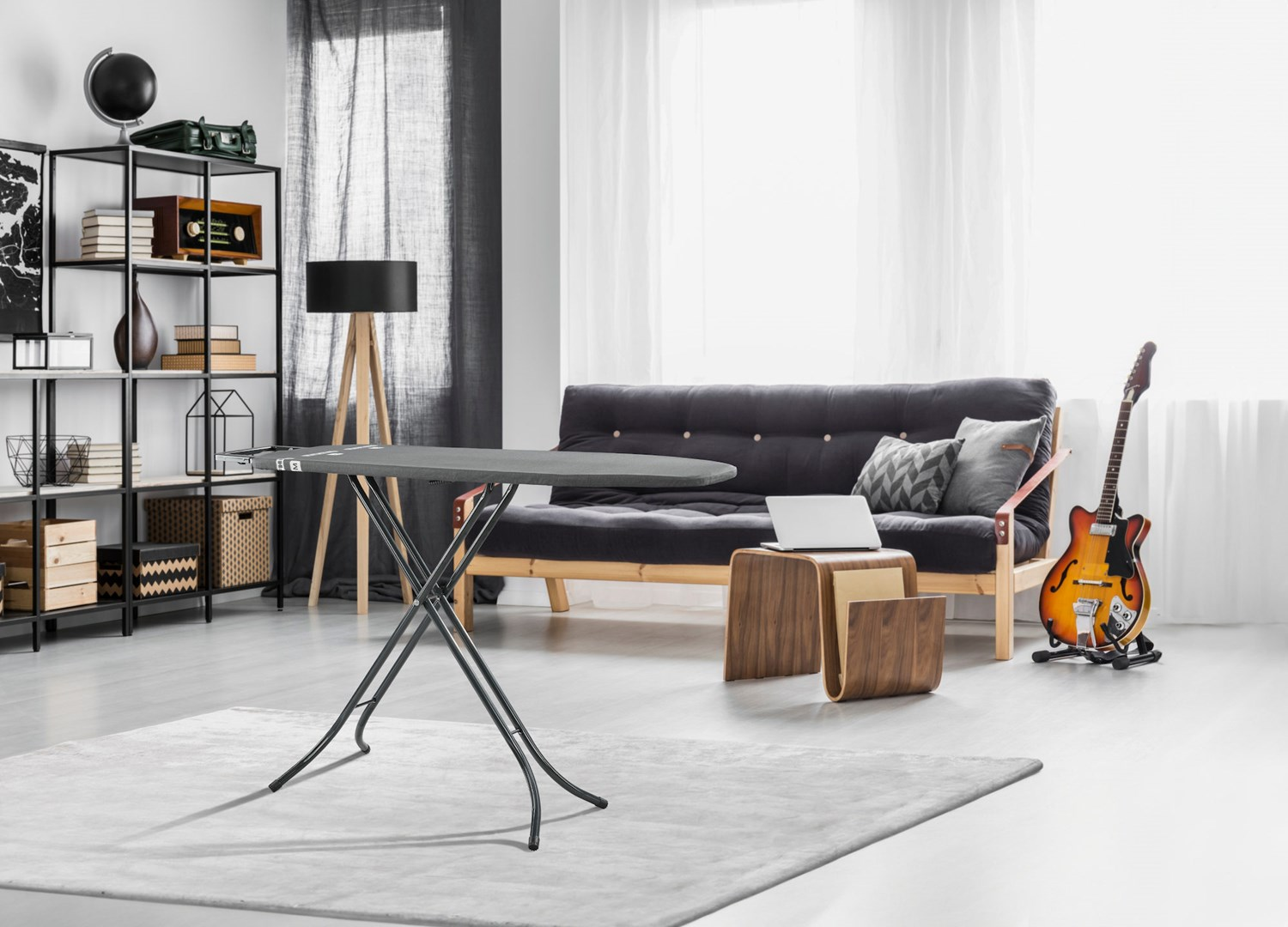 Salon z deską do prasowania, sofą, dywanem i gitarą. Pokój ma nowoczesny i jasny design.