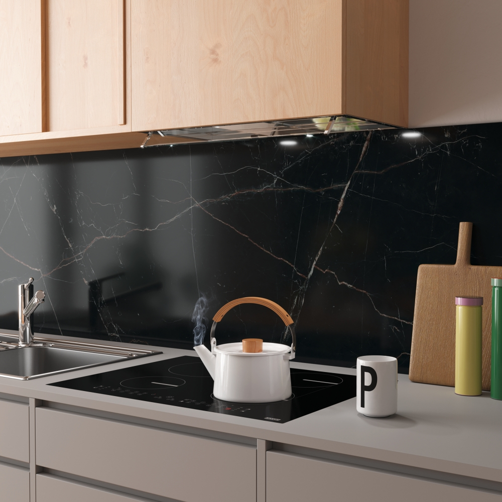 Mutfak sahnesi. Siyah ocak üzerinde beyaz su ısıtıcısı. Siyah mermer backsplash. Ahşap dolaplar ve kesme tahtaları.