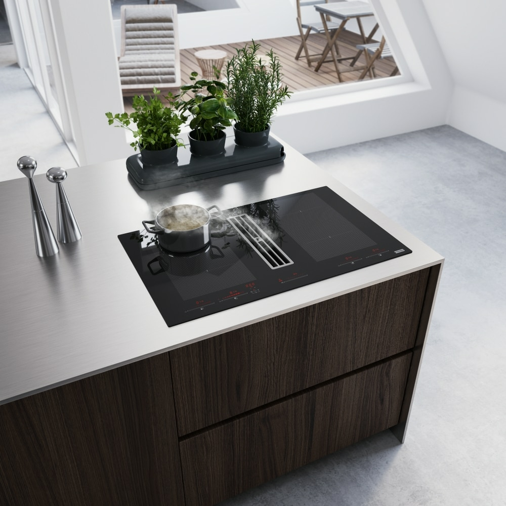 Un piano cucina con piano cottura integrato e piante in vaso.