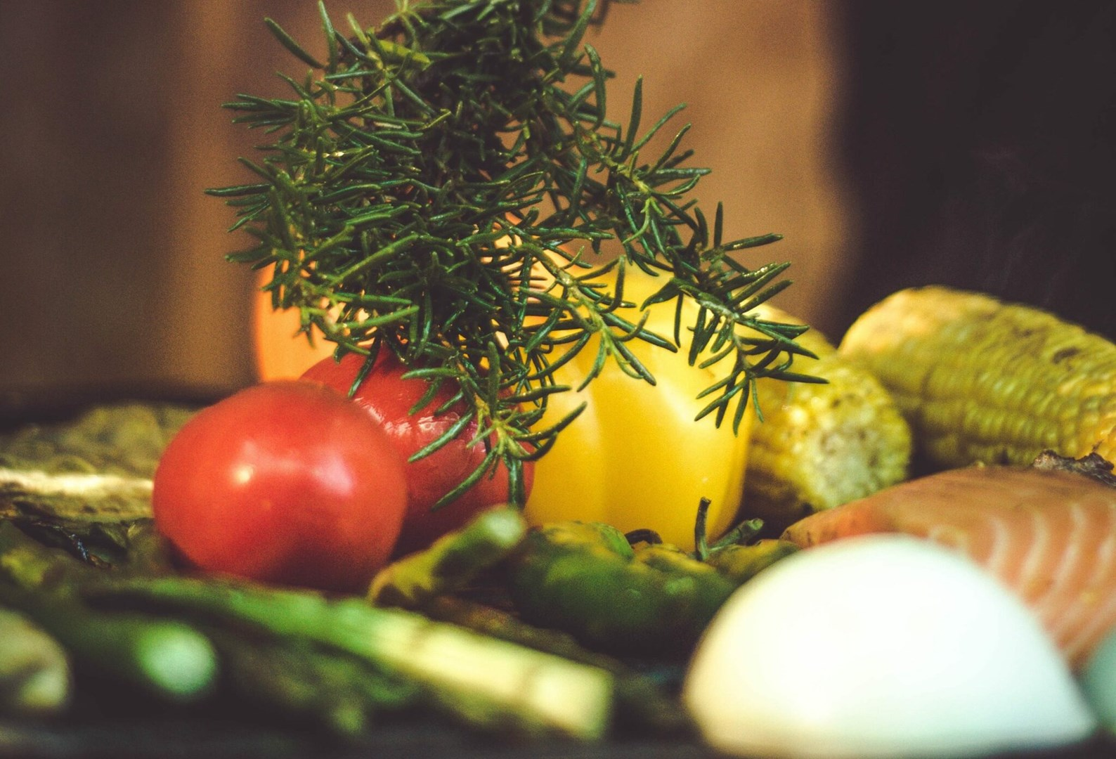 Tomaten, gelber Paprika, Mais und Lachs mit Rosmarin arrangiert. Zutaten für ein Essen, alles frisch und lebendig.