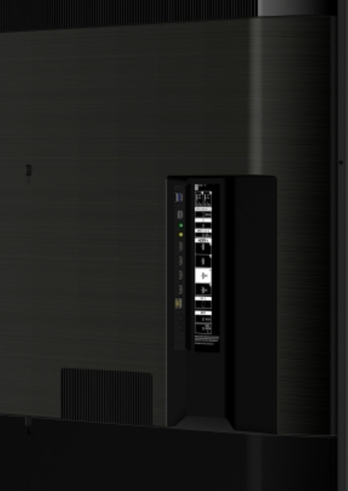 Tył dużego czarnego telewizora z panelem portów połączeniowych. Porty obejmują HDMI, USB i inne. Czarna powierzchnia.