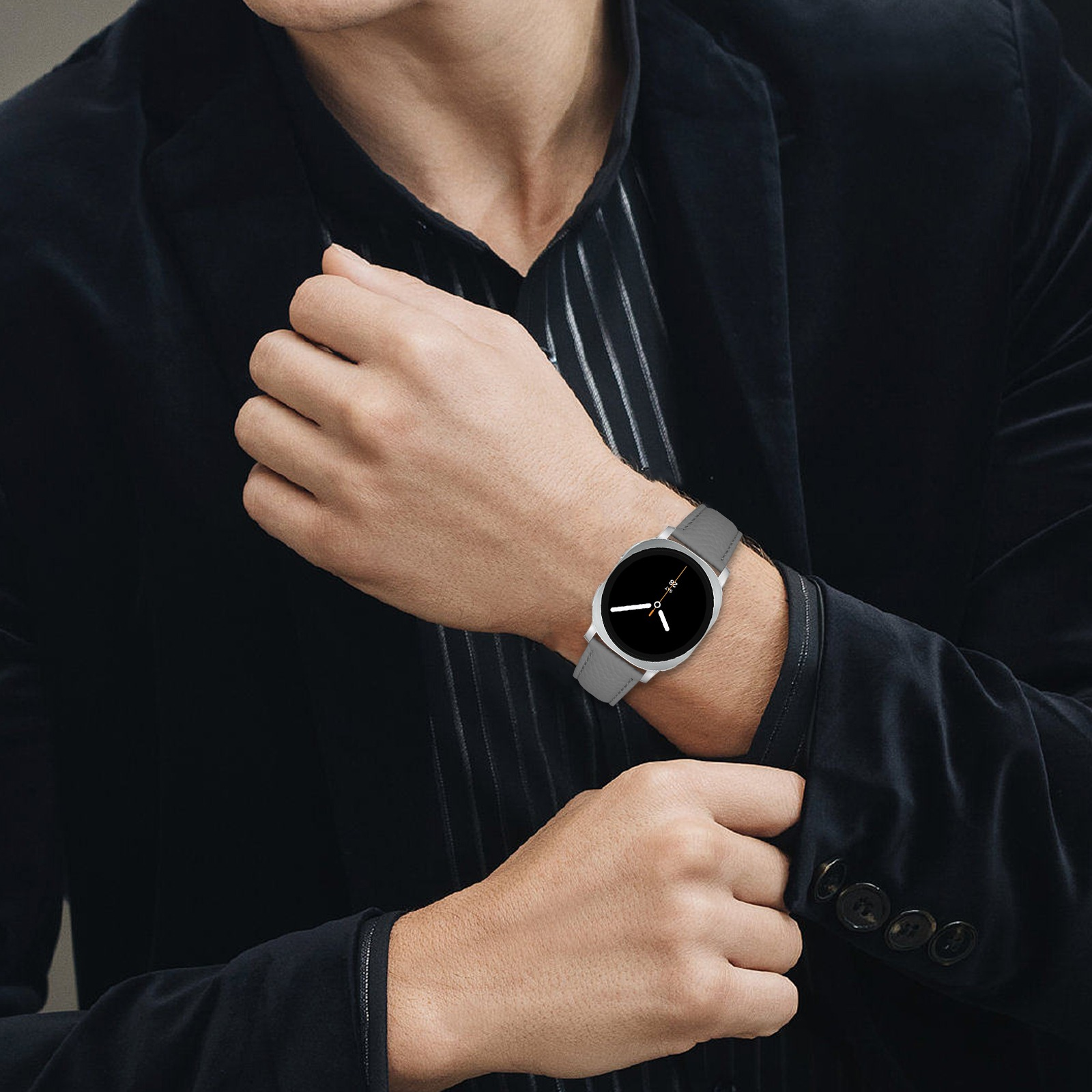 Mann trägt eine Uhr mit grauem Armband. Schwarzer Anzug. Uhr zeigt die Zeit an. Dunkler Hintergrund.