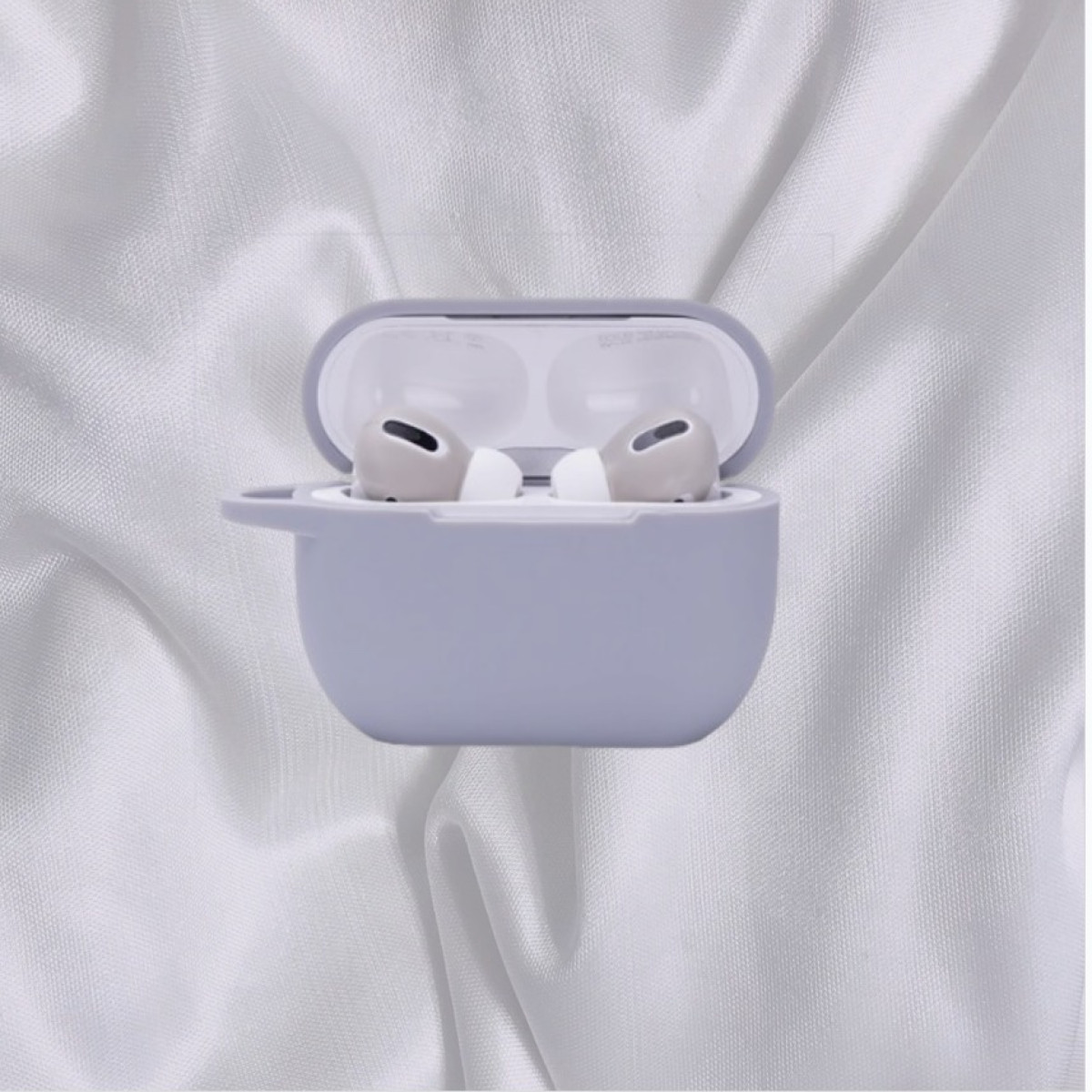 Funda gris para AirPods con tapa abierta, que revela auriculares grises. Fondo de tela blanca.