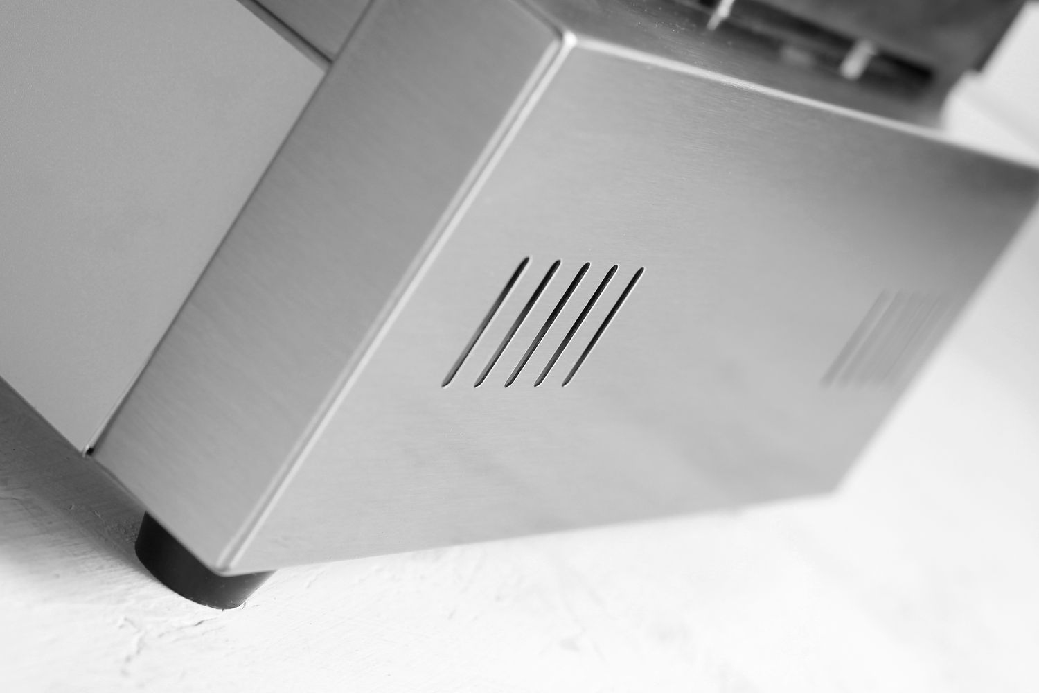 Nahaufnahme einer metallischen Oberfläche mit angewinkelten Lüftungsschlitzen.