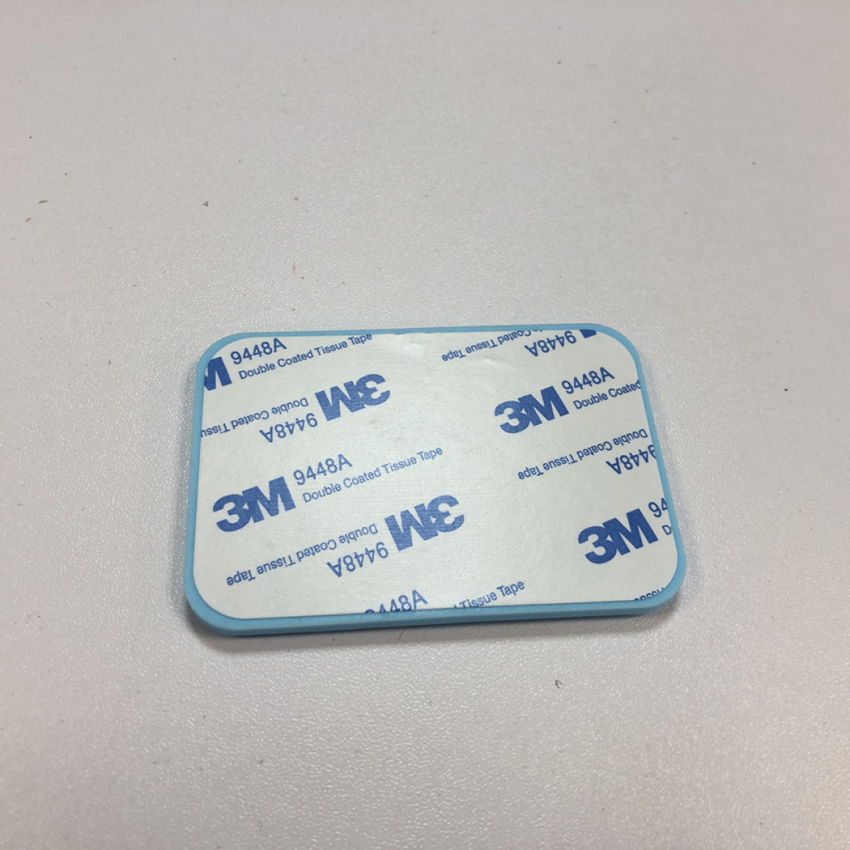Mały niebieski prostokąt dwustronnej taśmy klejącej. Widoczna jest nazwa marki 3M oraz informacje o produkcie.