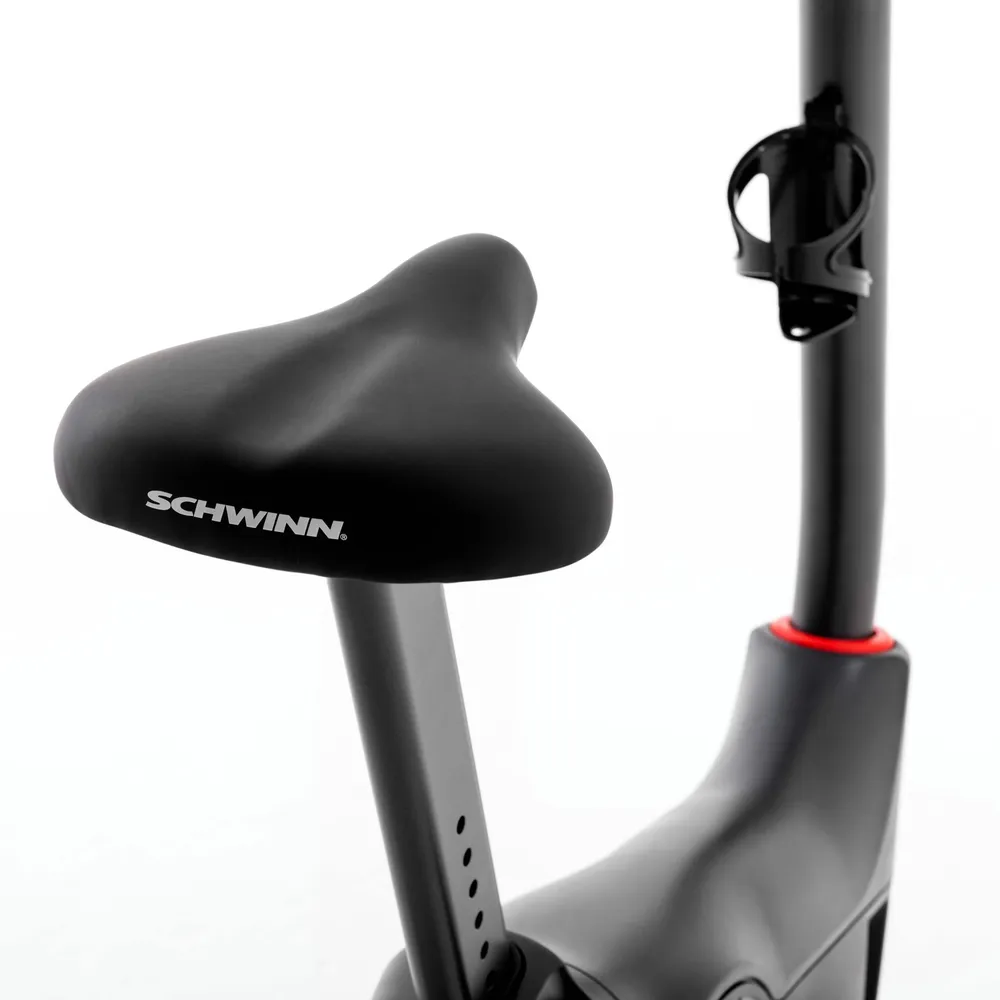 Un siège de vélo d'exercice Schwinn noir est montré. Le siège est noir et porte le nom de la marque Schwinn.