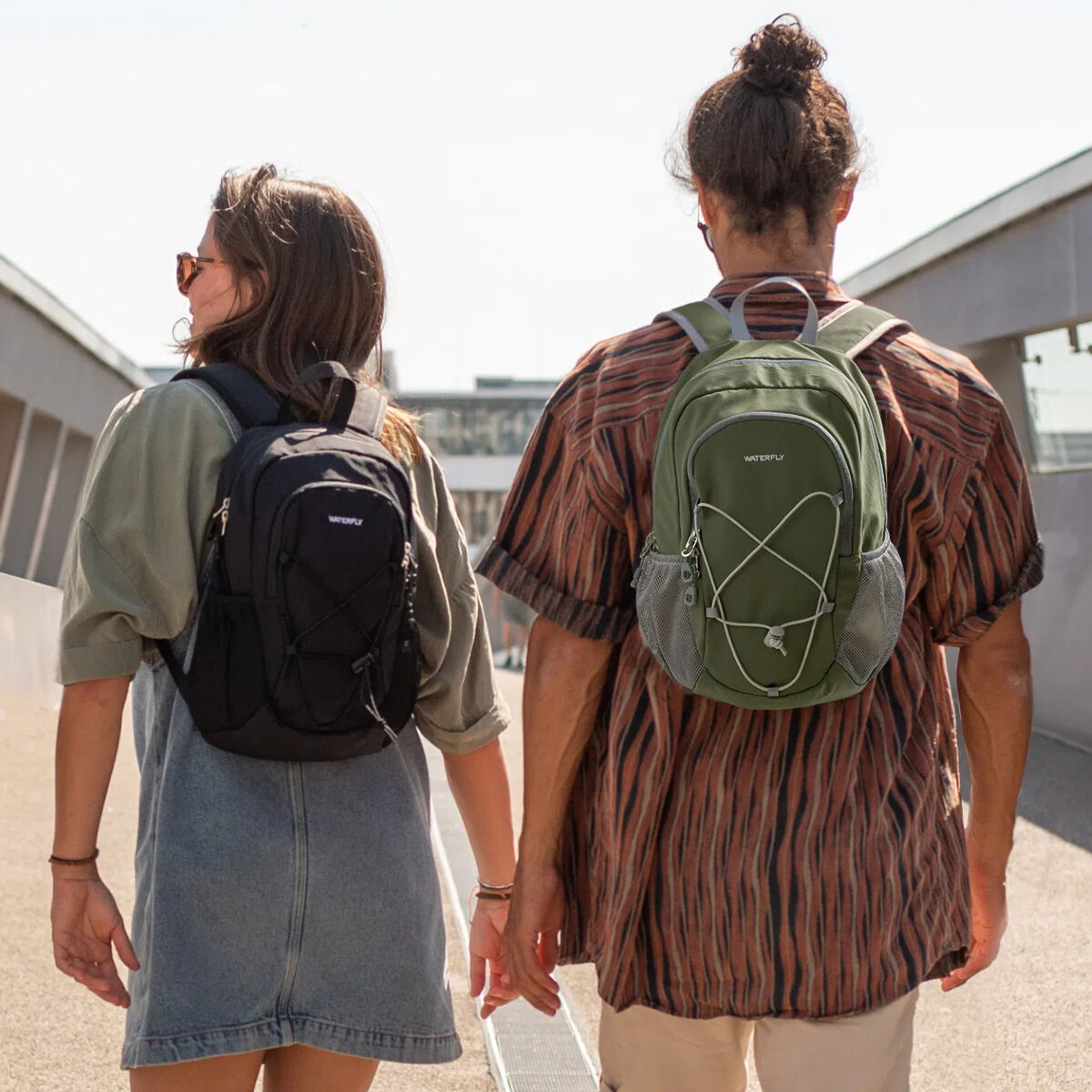Due persone che camminano, con zaini. Uno nero, uno verde. Tenendosi per mano.