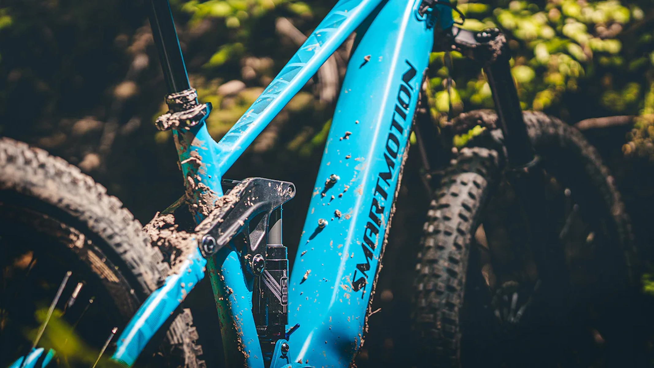 Nahaufnahme eines schlammbedeckten, blauen Mountainbike-Rahmens mit Smartmotion-Logo.