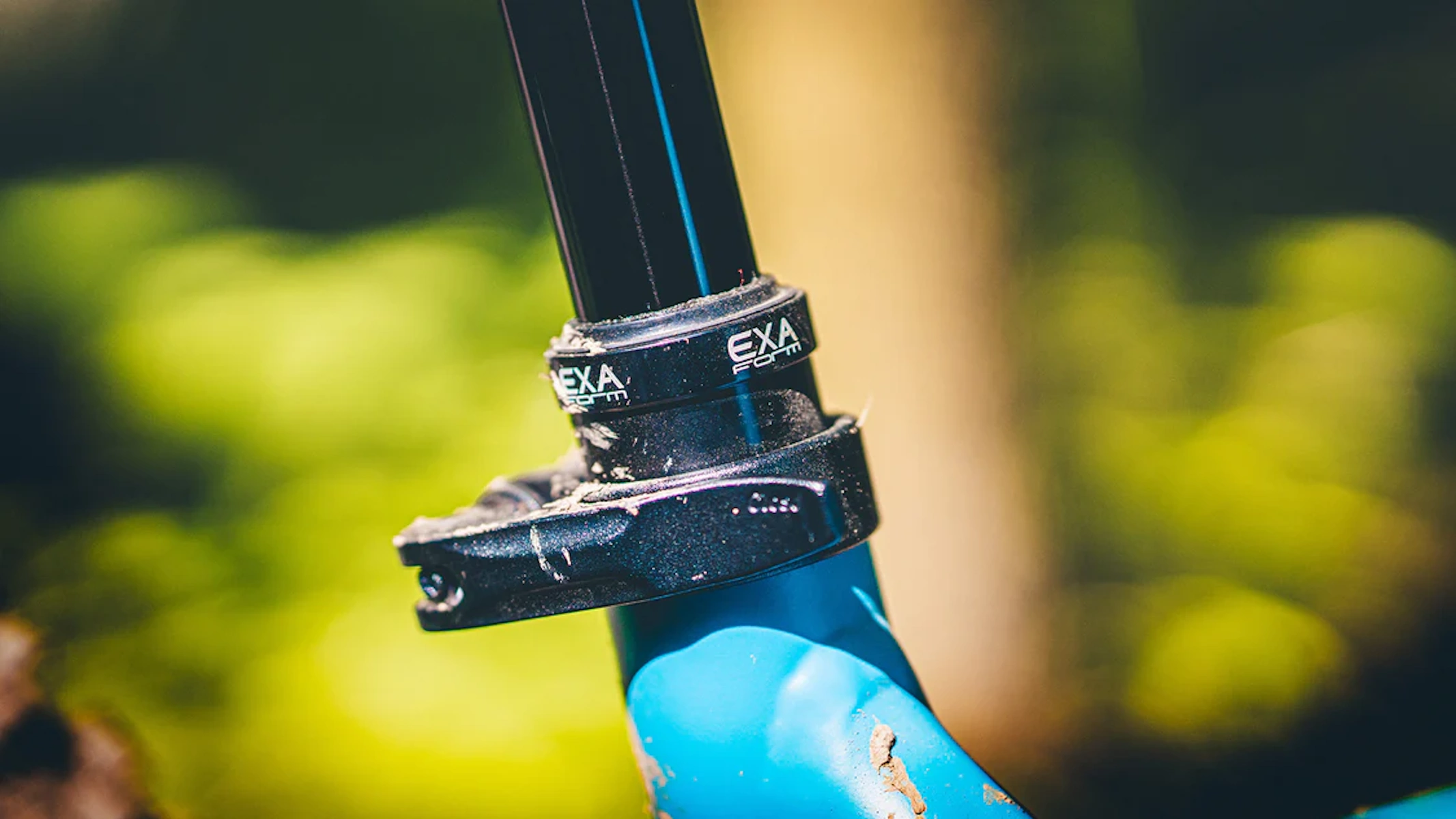 Nahaufnahme des EXA Form Sattelstützenaufsatzes an dem blauen Fahrrad, in einer Waldumgebung.