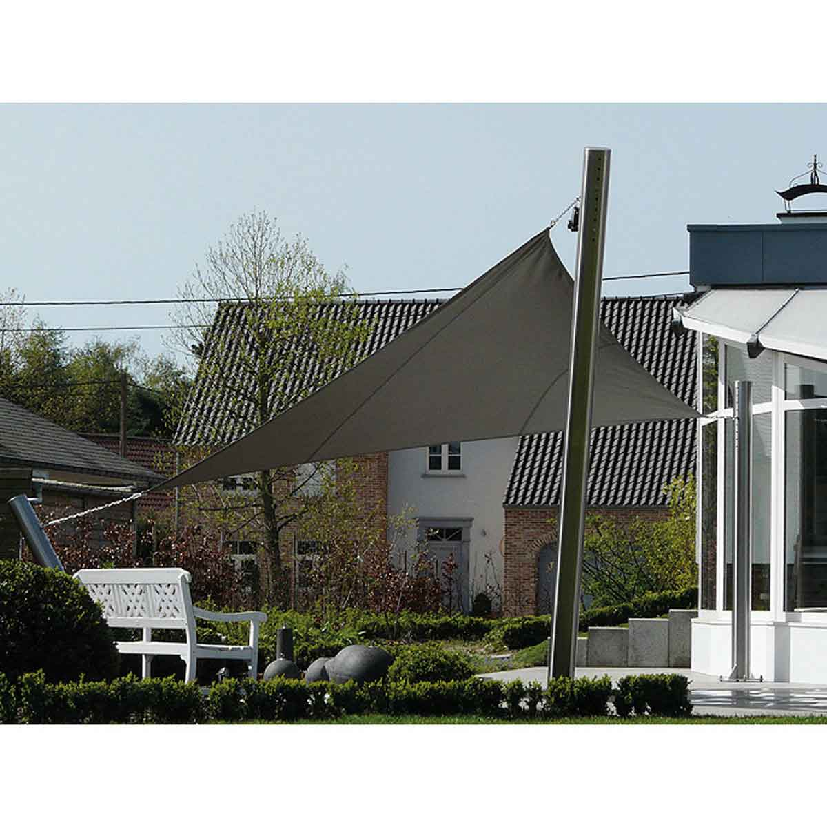 Une voile d'ombrage triangulaire est tendue entre un poteau et une maison. Un banc blanc est à proximité.