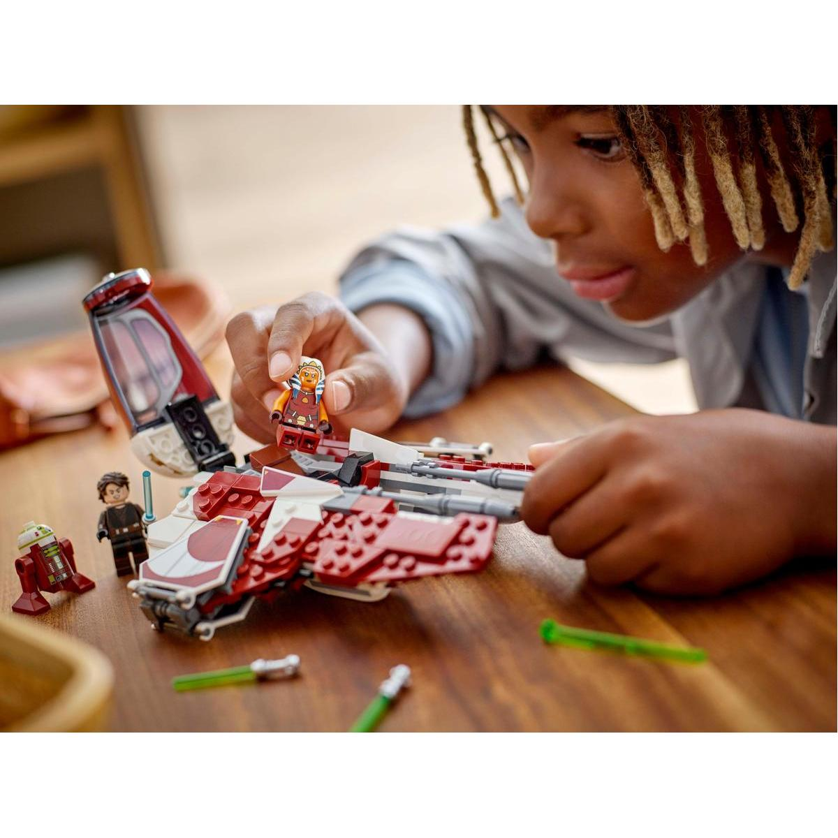 Ein Junge baut ein Lego Star Wars Set zusammen. Das Set enthält ein kleines rot-weißes Raumschiff und Minifiguren.