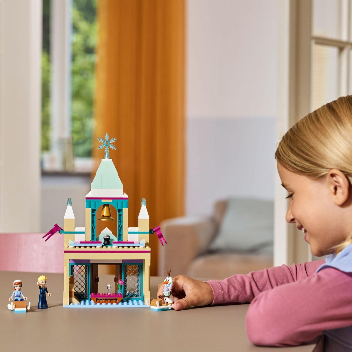 Dziewczynka bawiąca się zestawem Lego Frozen, z zamkiem i figurkami Anny i Elsy.