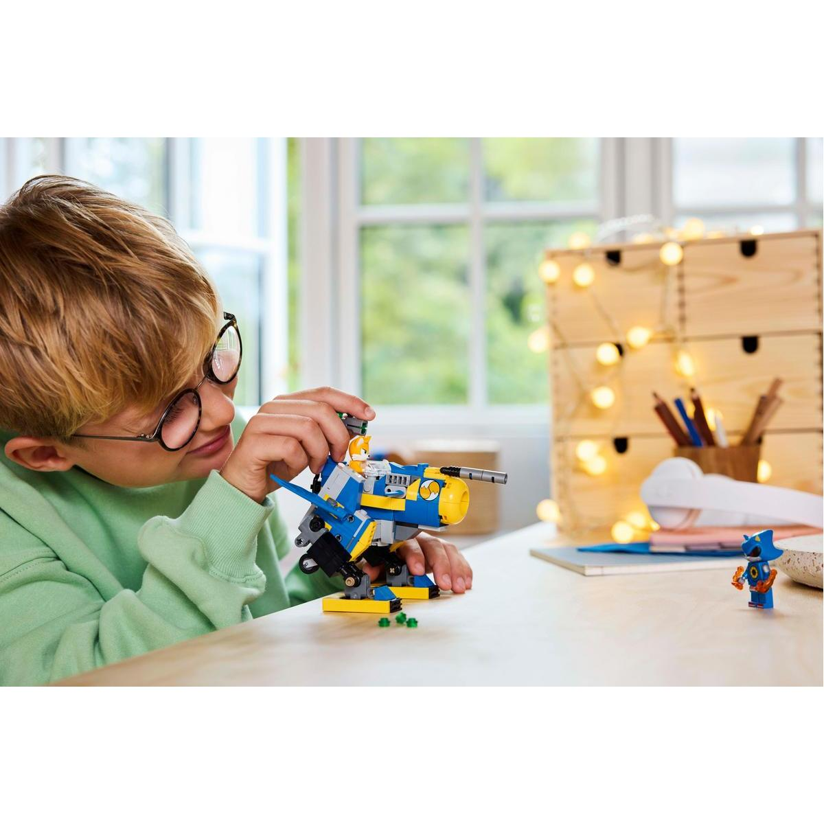 Chłopiec buduje statek kosmiczny Lego. Obok statku stoi figurka Lego.