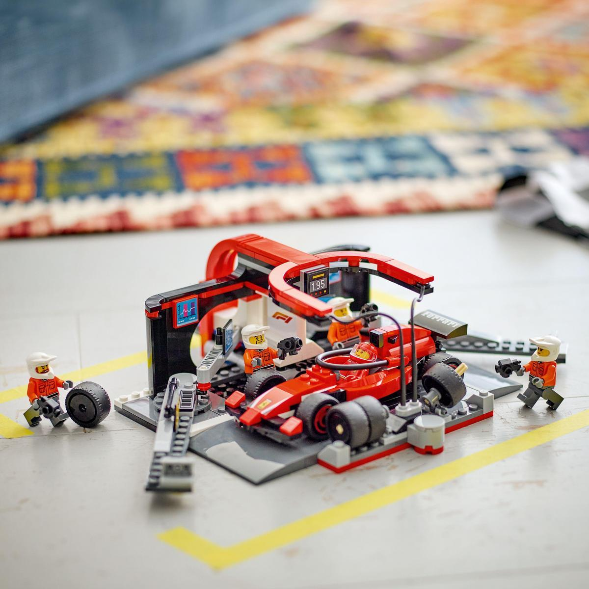 Ein Lego F1-Rennwagen befindet sich in einer Garage mit Menschen, Werkzeugen und einer Strecke, alles aus Lego-Steinen.