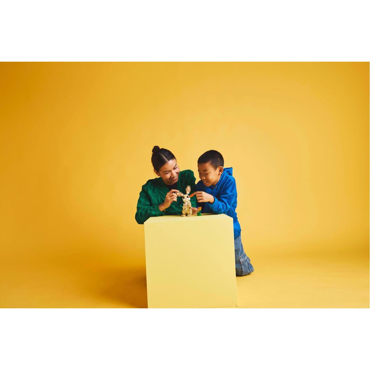 Kobieta i dziecko wspólnie budują model Lego na żółtej powierzchni.