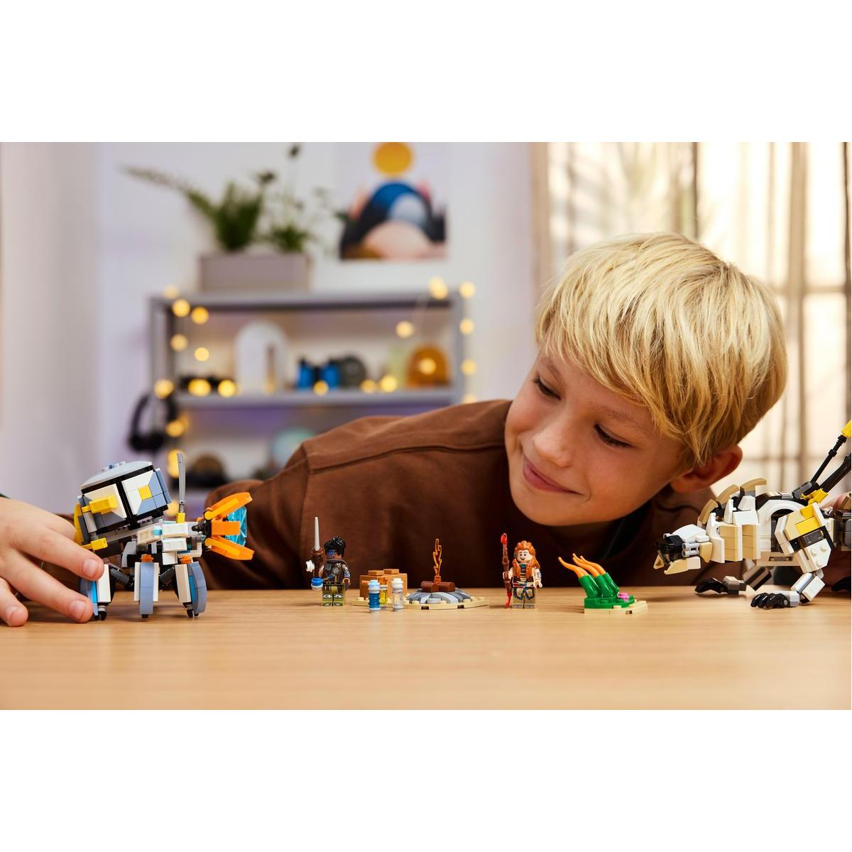Ein Junge betrachtet Lego-Modelle. Es gibt mehrere Lego-Figuren und ein Gebäude. Der Hintergrund hat Lichter.