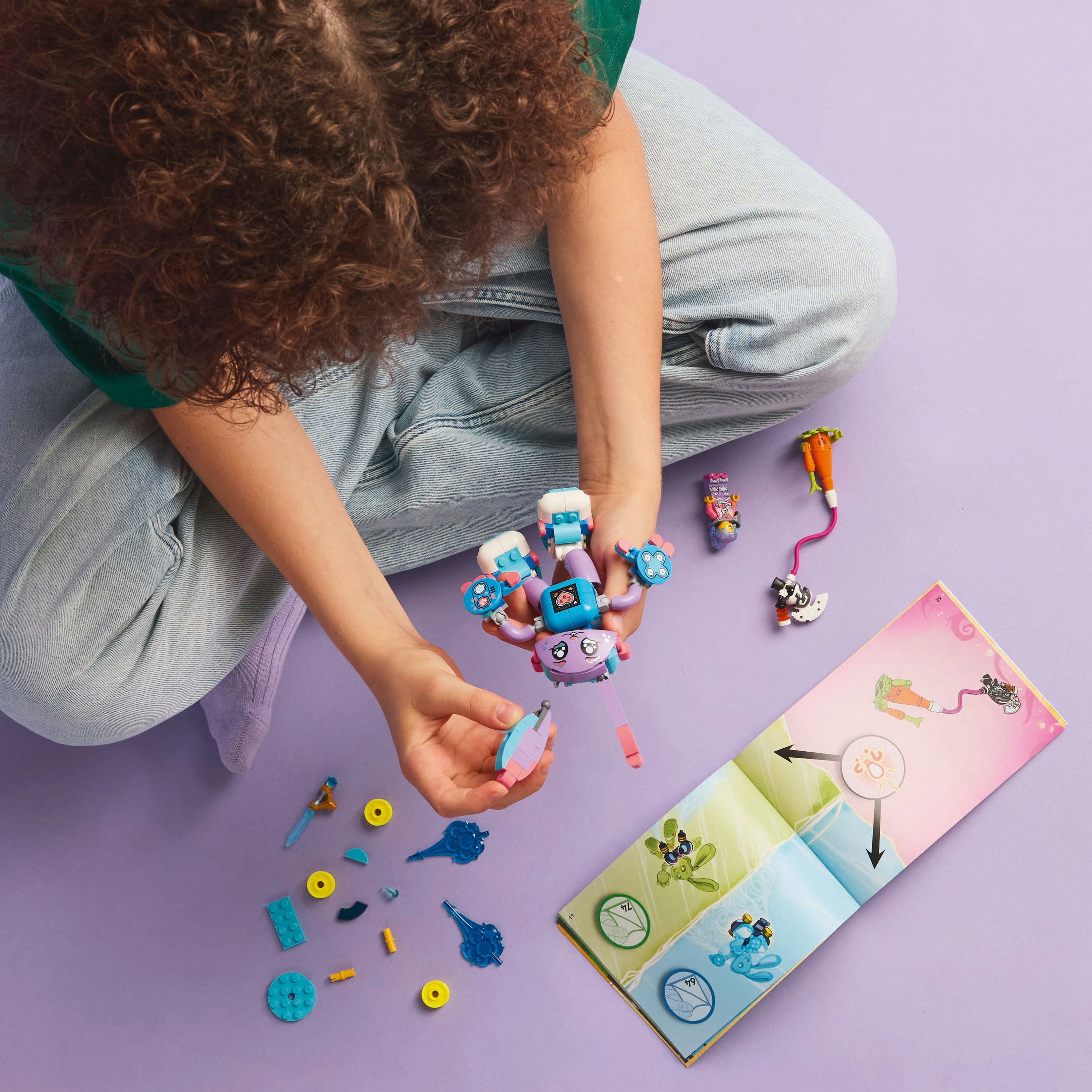 Osoba montuje figurę Lego z małymi elementami rozrzuconymi na fioletowej powierzchni.
