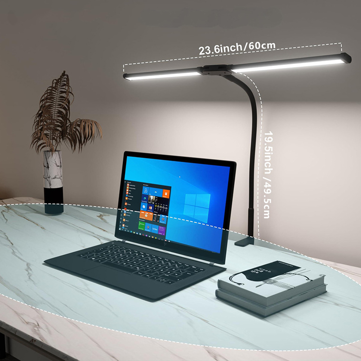 Una scrivania con un laptop, un libro e una lampada da scrivania con due barre luminose che illuminano la superficie.