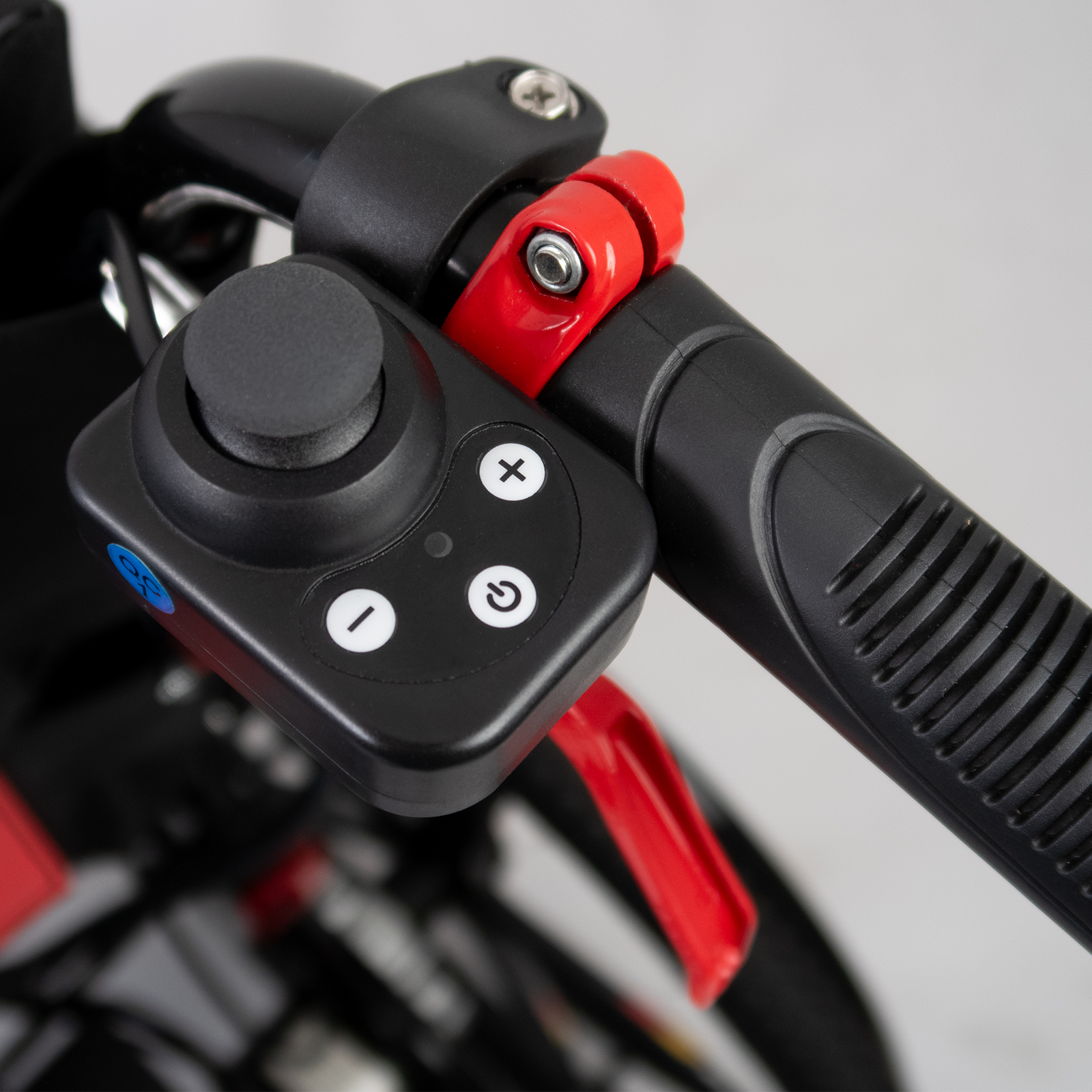 Nahaufnahme eines schwarzen Bedienfelds an einem Rollstuhl. Es hat einen Joystick und Tasten mit Plus- und Minuszeichen.