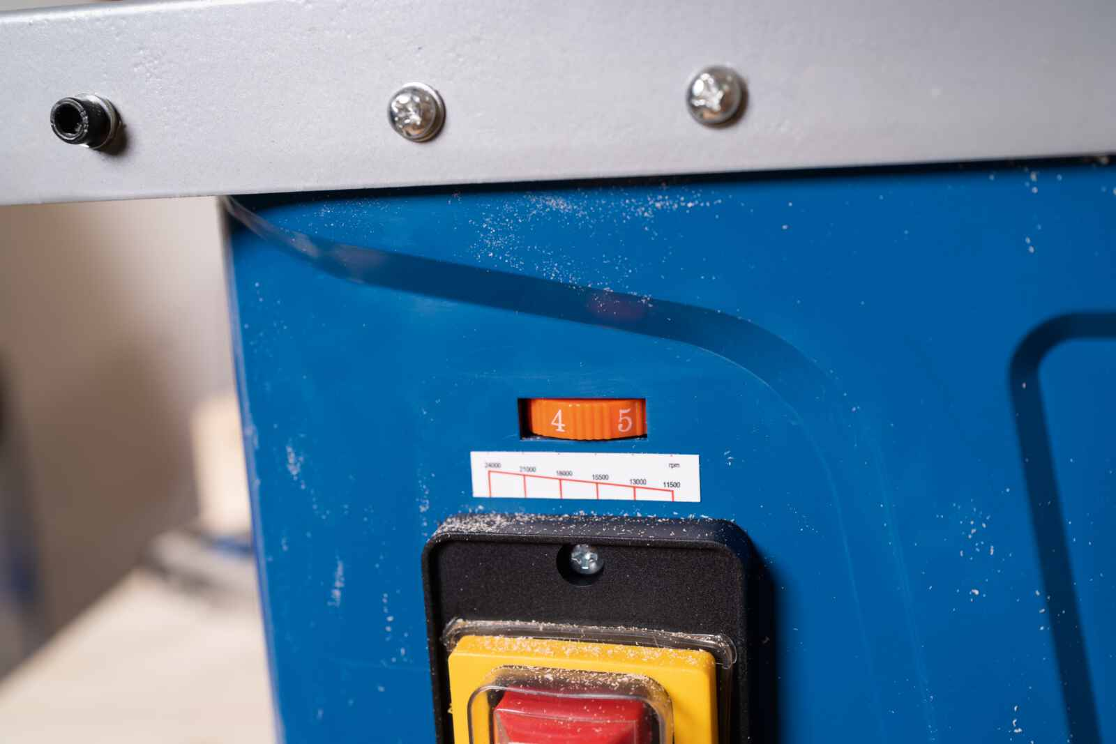 Primo piano di un pannello di controllo su una macchina blu, che mostra un'impostazione di velocità di 4 e un interruttore di alimentazione.