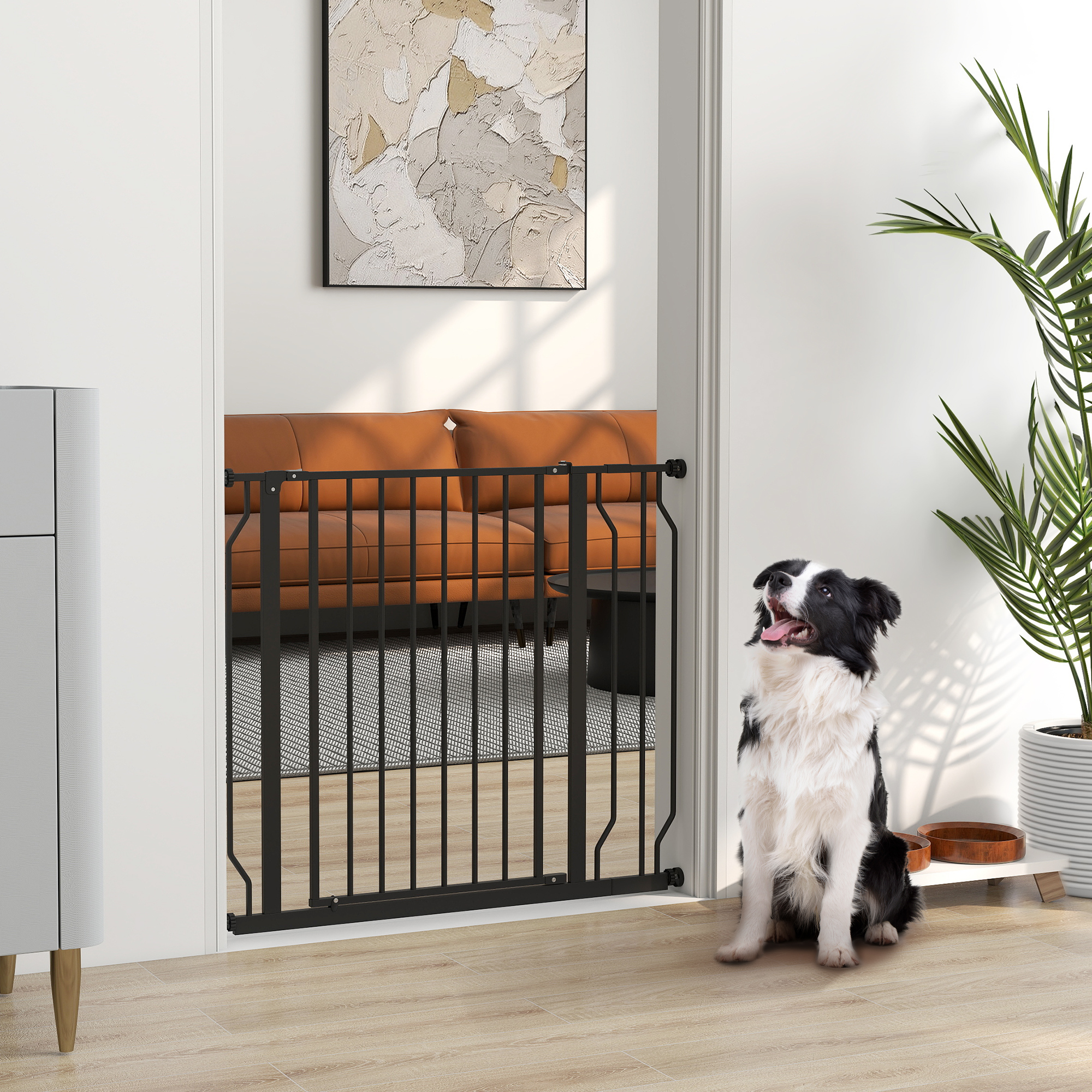 Un Border Collie blanco y negro se sienta junto a una puerta metálica negra para mascotas en un entorno doméstico.