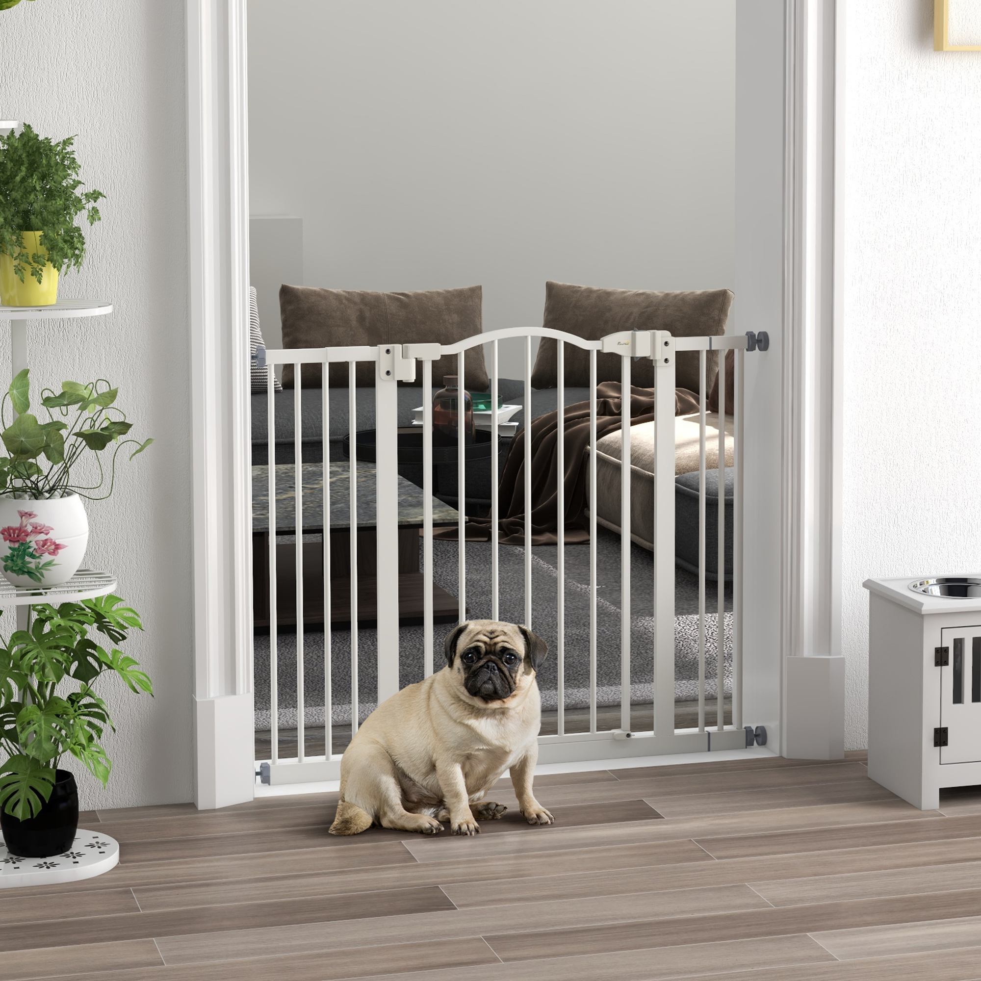 Un pug se sienta frente a una puerta metálica blanca para mascotas dentro de una casa.