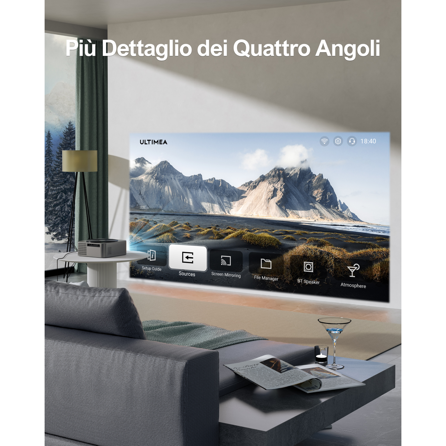 Un proiettore mostra una scena di montagna. Un divano e un tavolo sono in primo piano. Un bicchiere con una bevanda è sul tavolo.