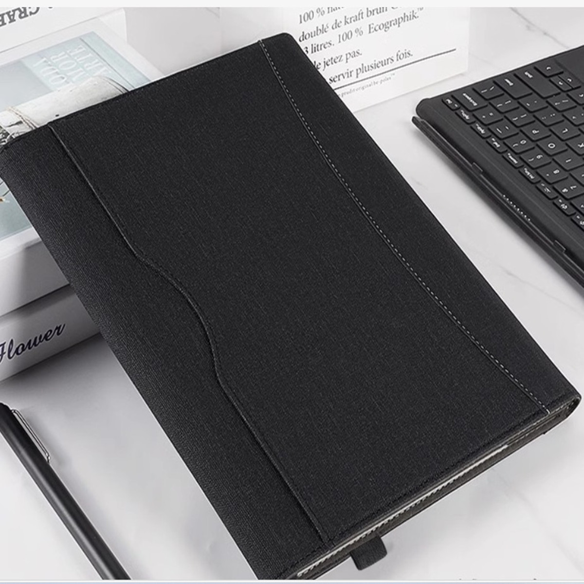 Un astuccio nero con penna e tastiera. L'astuccio è aperto su una superficie bianca con libri.