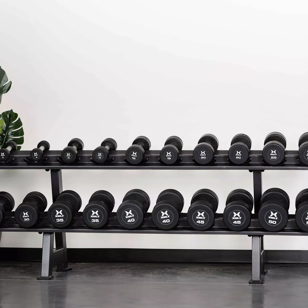 Gym met gewichten. Twee rekken met dumbbells. Zwarte dumbbells. Witte muurachtergrond.