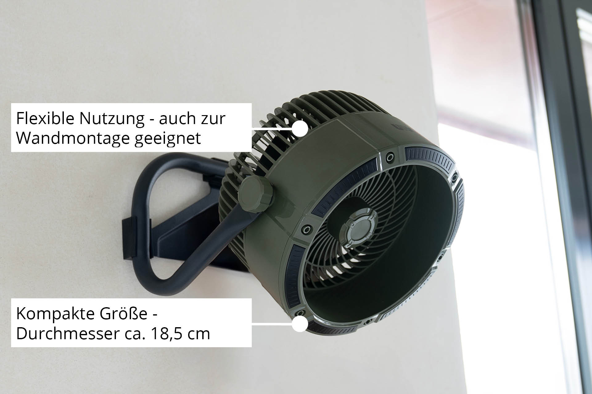 Grüner Ventilator an der Wand, schwarzer Griff, Text auf Deutsch.