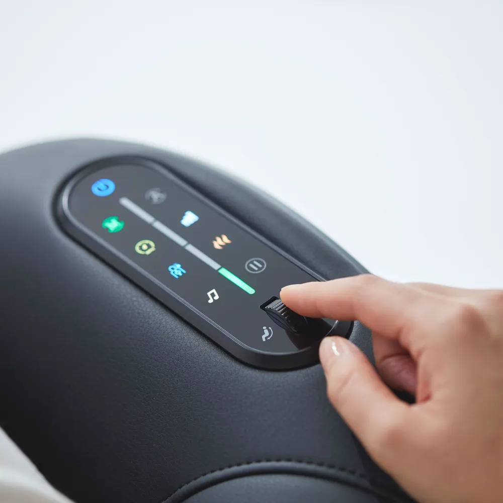 Une main ajuste les commandes sur un fauteuil de massage noir. Les boutons sont éclairés.