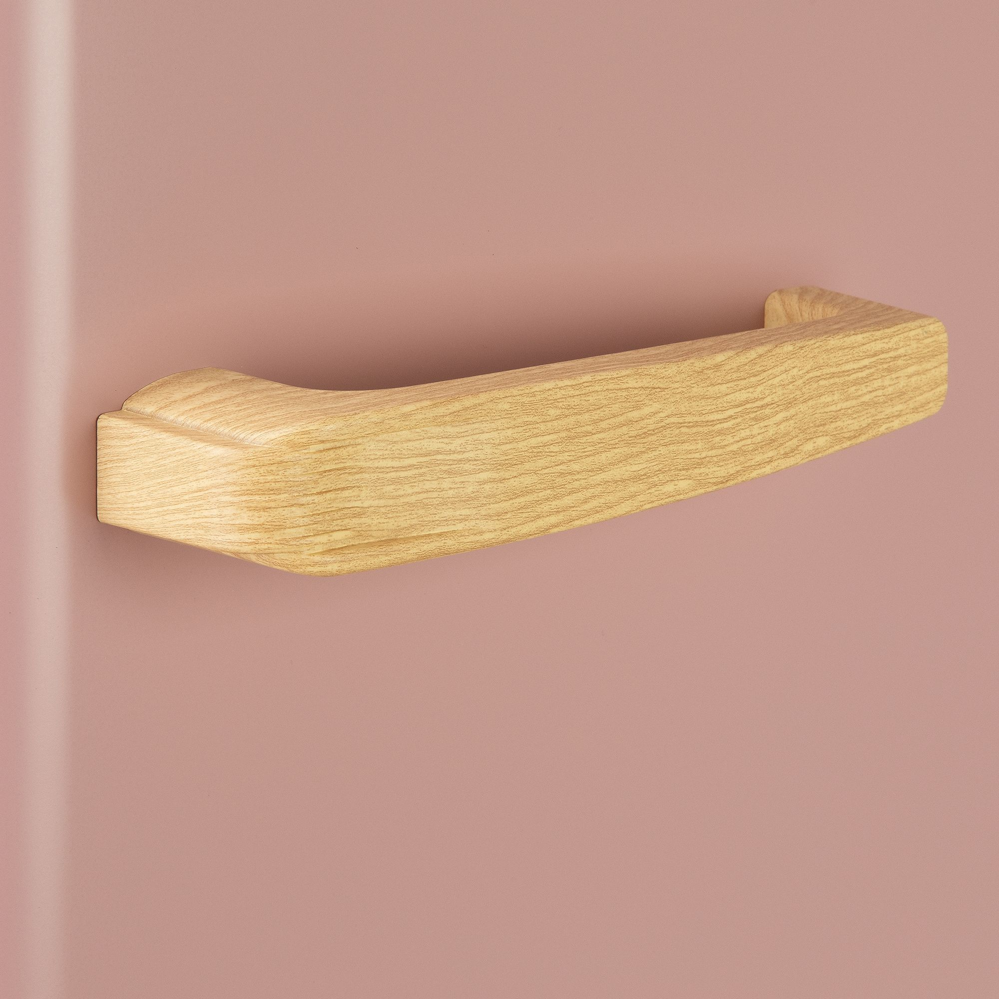 Una maniglia in legno attaccata a una superficie rosa. La maniglia è rettangolare con parte superiore curva e venatura.