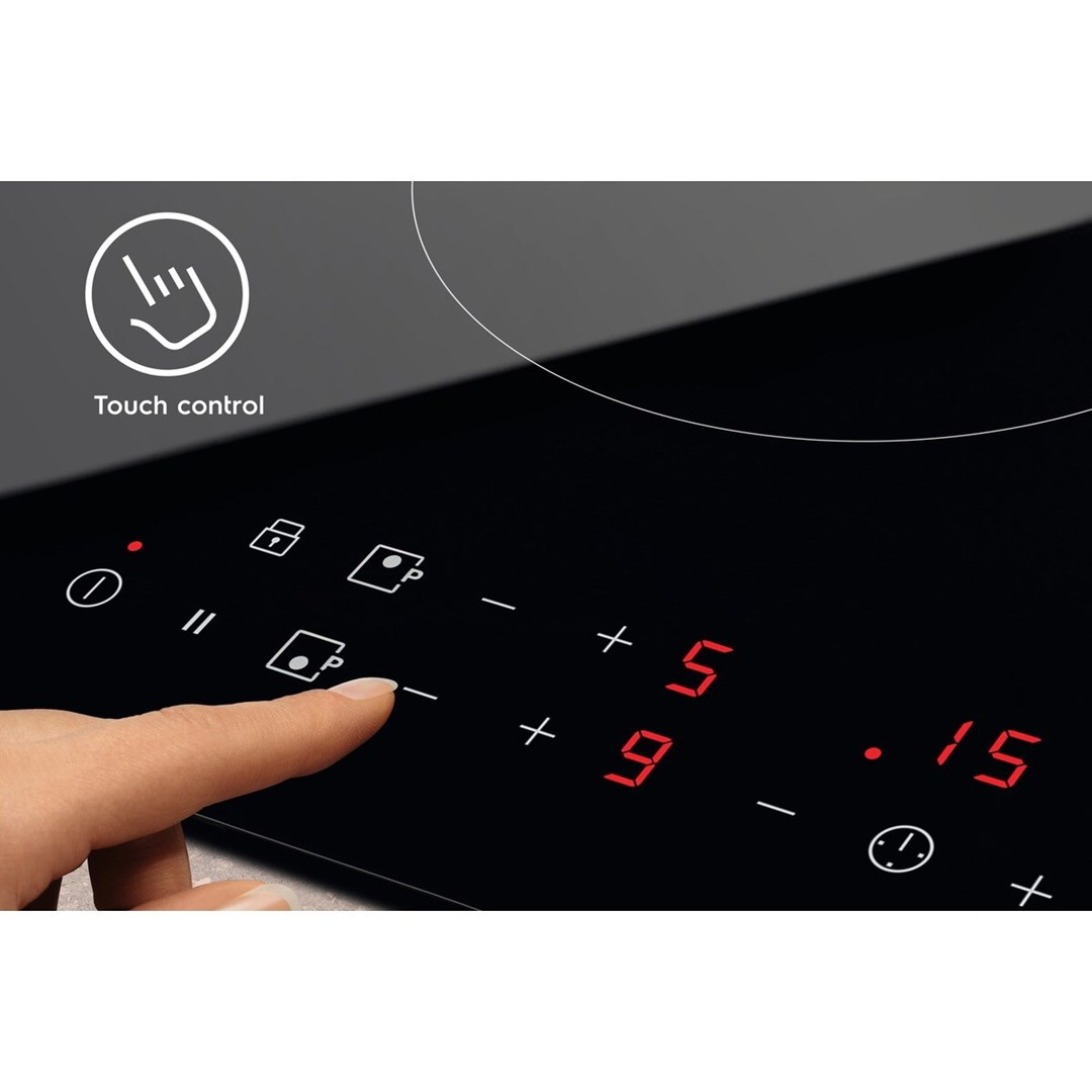 Zbliżenie panelu sterowania czarnej płyty grzejnej, dłoń dotykająca przycisku, z czerwonymi cyframi.