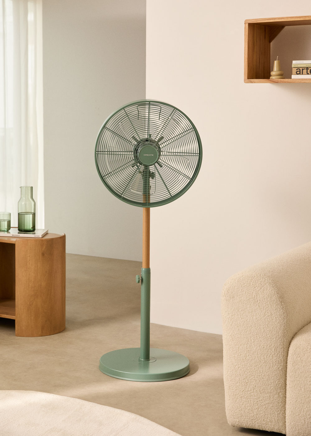 Ventilador verde, mesa de madera con objetos, sofá blanco y pared.