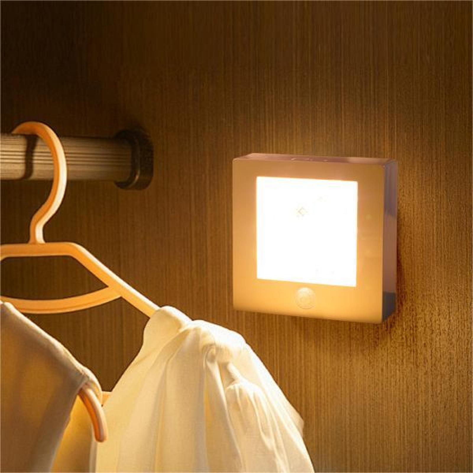 Eine weiße quadratische LED-Leuchte an einer Holzwand, mit Kleiderstange und hängenden Kleidern.