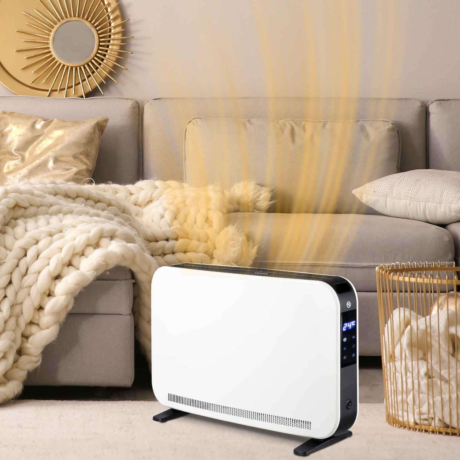 Weißer Elektroheizer in einem Wohnzimmer. Hitzewellen sind sichtbar. Sofa und goldene Dekorationen im Hintergrund.